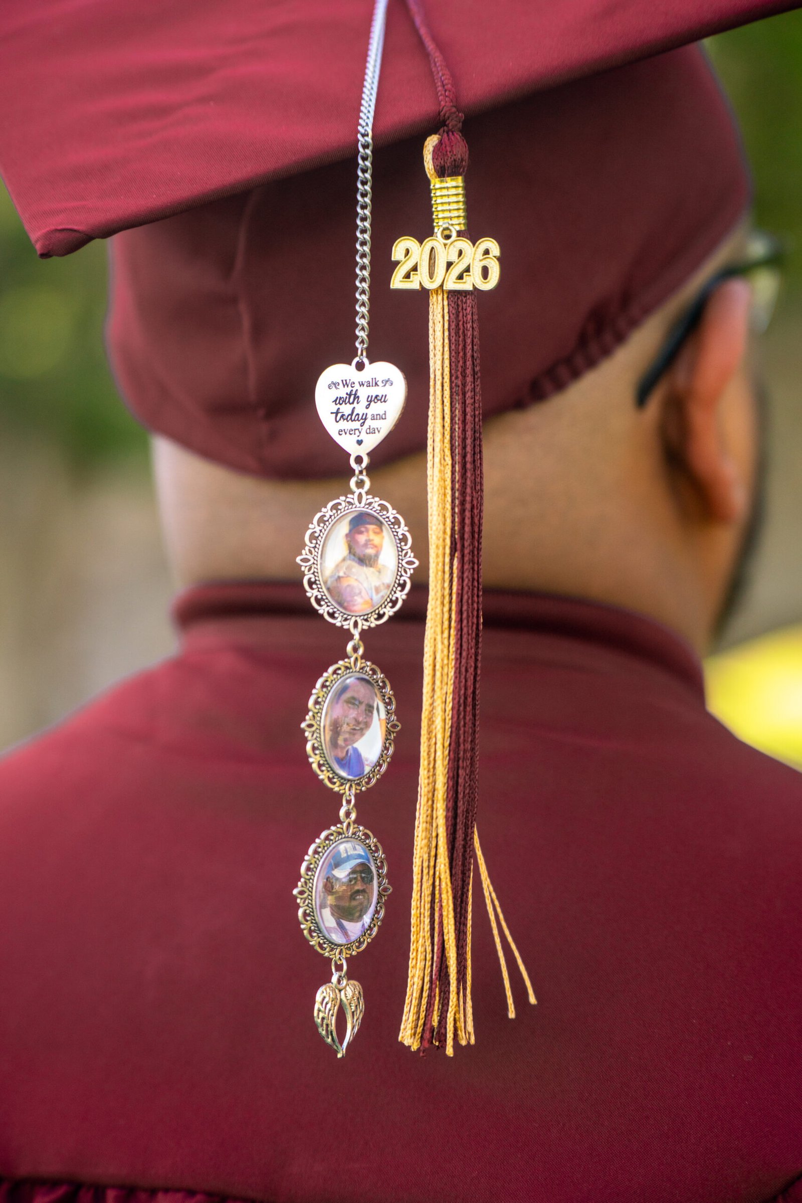 Close view of a maroon graduation cap decorated with photo charms and a tassel.