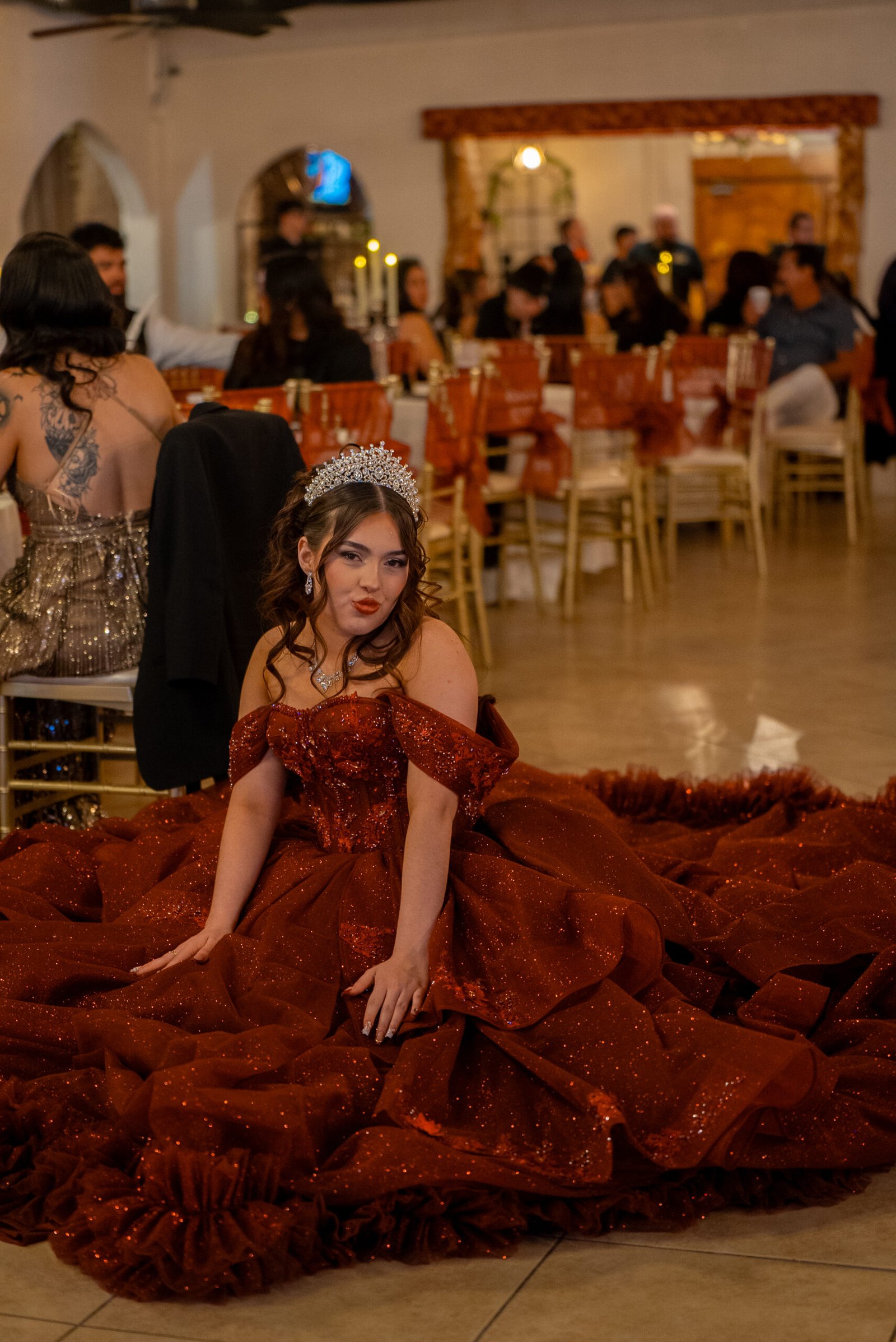 Young woman in a red dress sits on the floor during the celebration.
