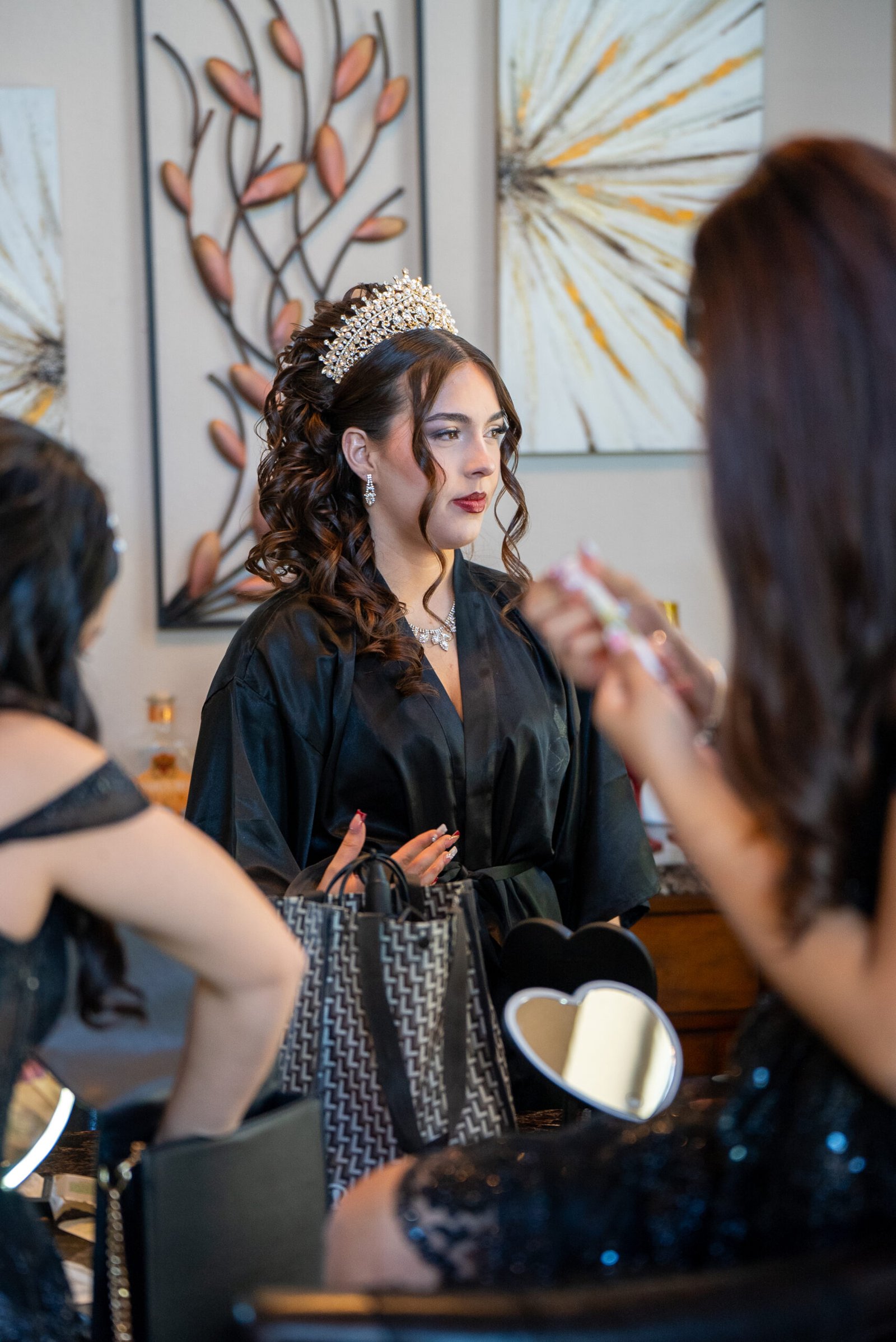 Quinceañera wearing a tiara as she gets ready with help from an attendant.